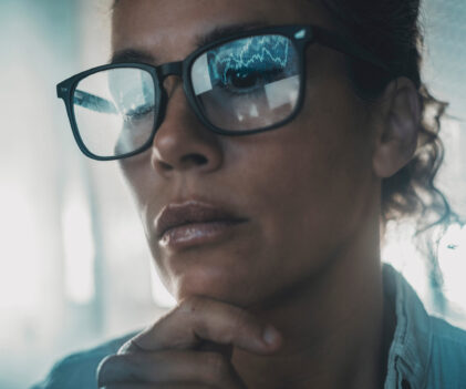 Technology concept people portrait with digital charts reflected on eyewear. One woman in business online modern activity looking a display with reflection on glasses. Concept of businesswoman alone